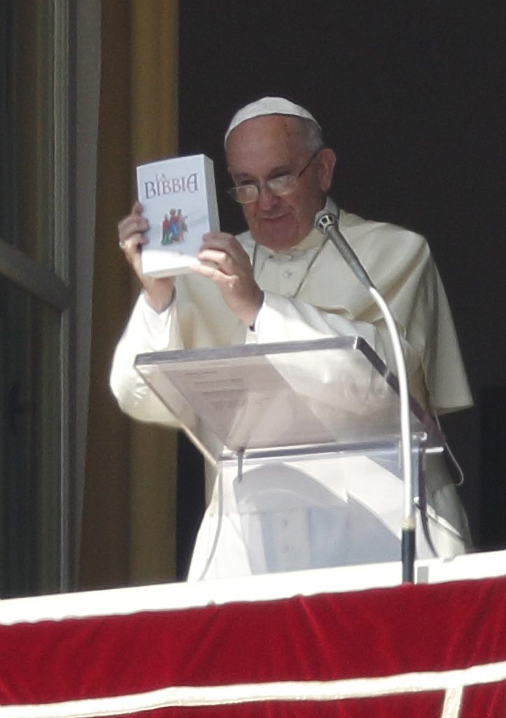 Pope Francis holds up a Bible as he promotes reading of the Bible during his Angelus delivered from the window of his studio overlooking St. Peter's Square at the Vatican in this Oct. 5, 2014, file photo. (CNS photo/Paul Haring) See DEI-VERBUM-ANNIVERSARY Nov. 20, 2015.